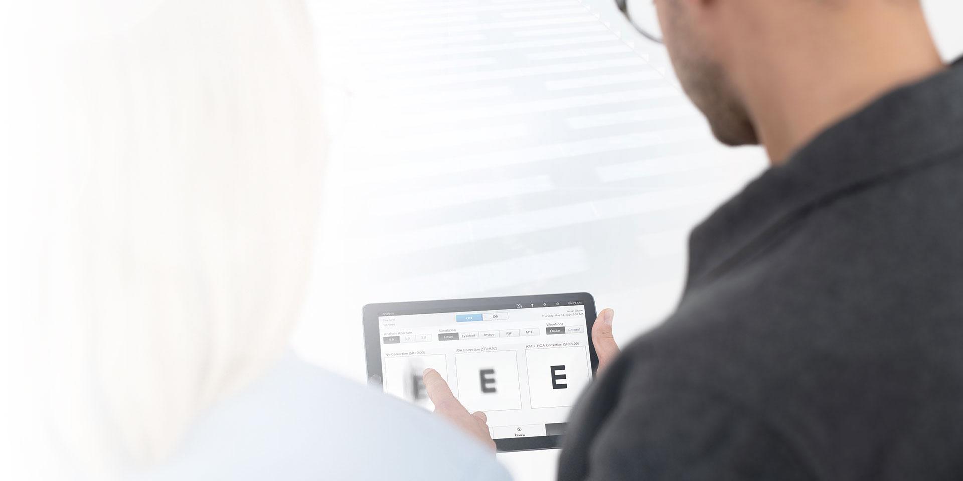 Photo coupée de deux personnes prise par-dessus l’épaule, le visage n’est pas visible. Des personnes regardent un iPad sur lequel les résultats visuels sont affichés. 