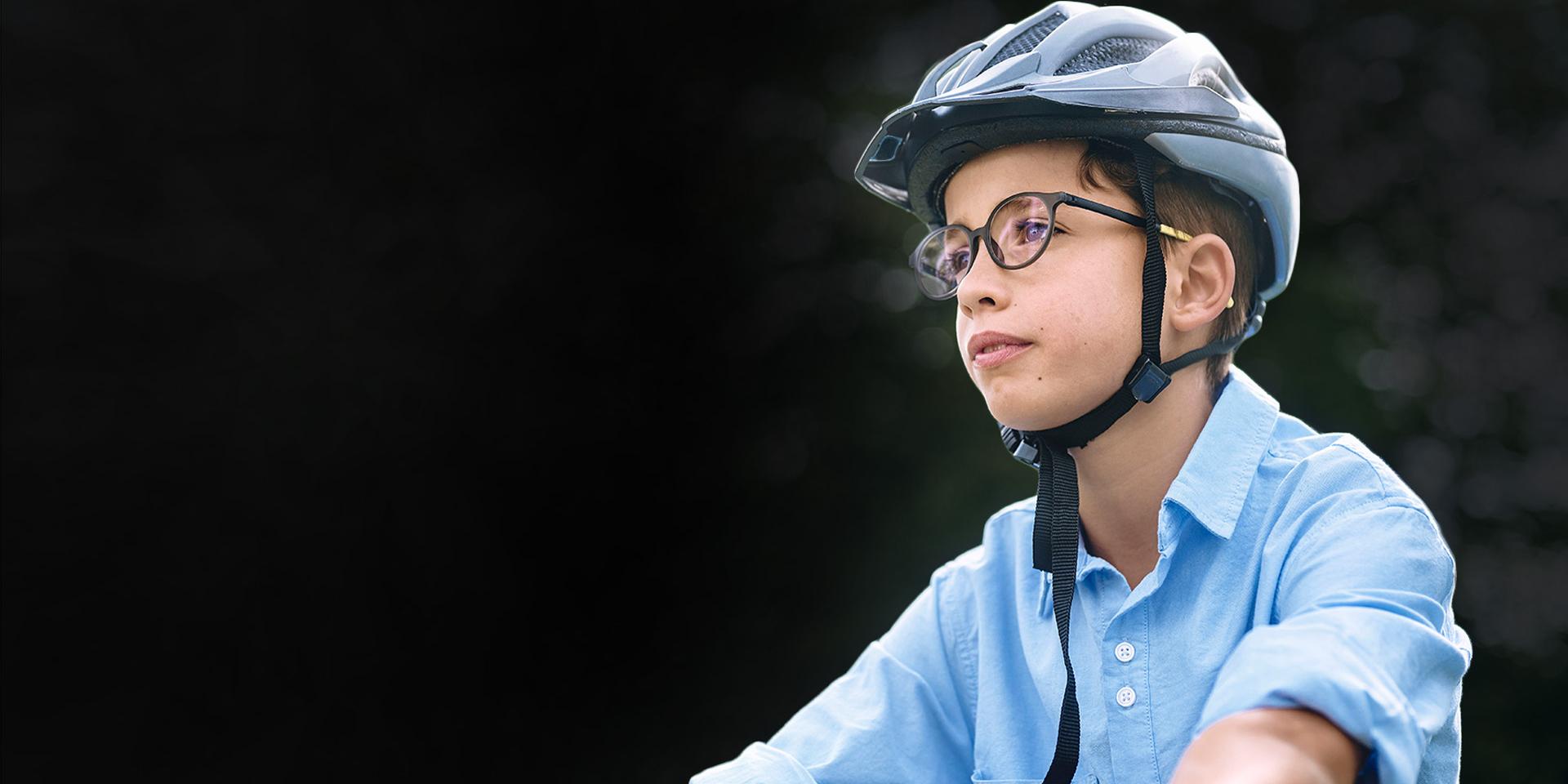 Un jeune garçon portant des lunettes et un casque semble rouler à vélo.