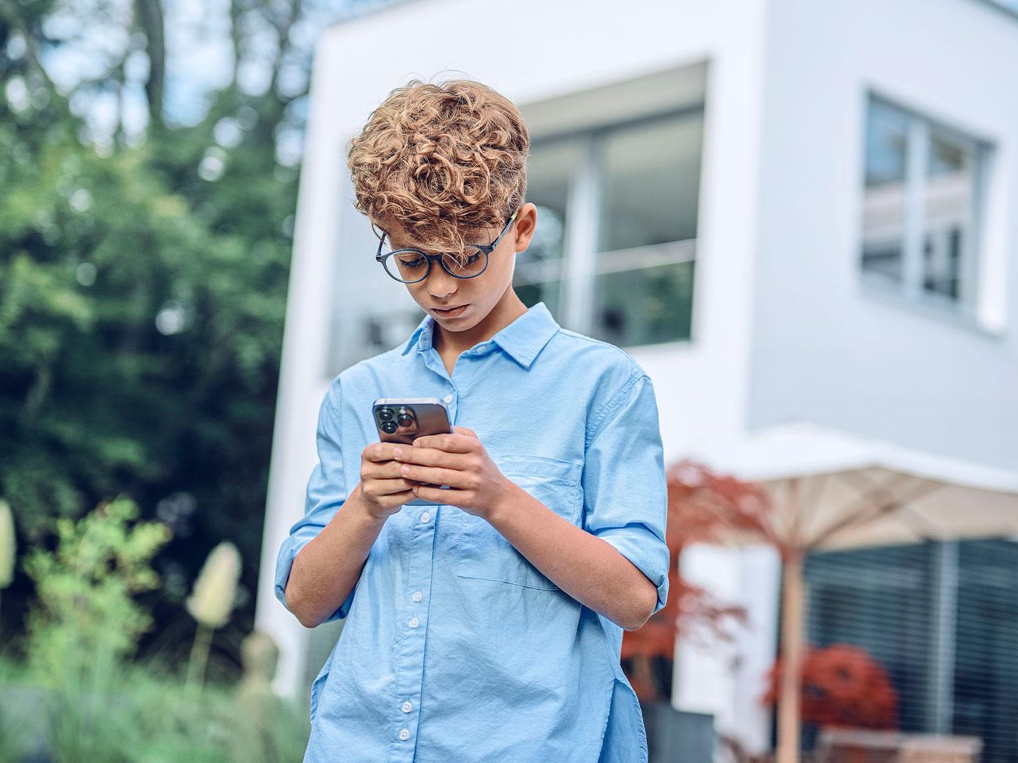 Jeune garçon à l&apos;extérieur regardant son téléphone.