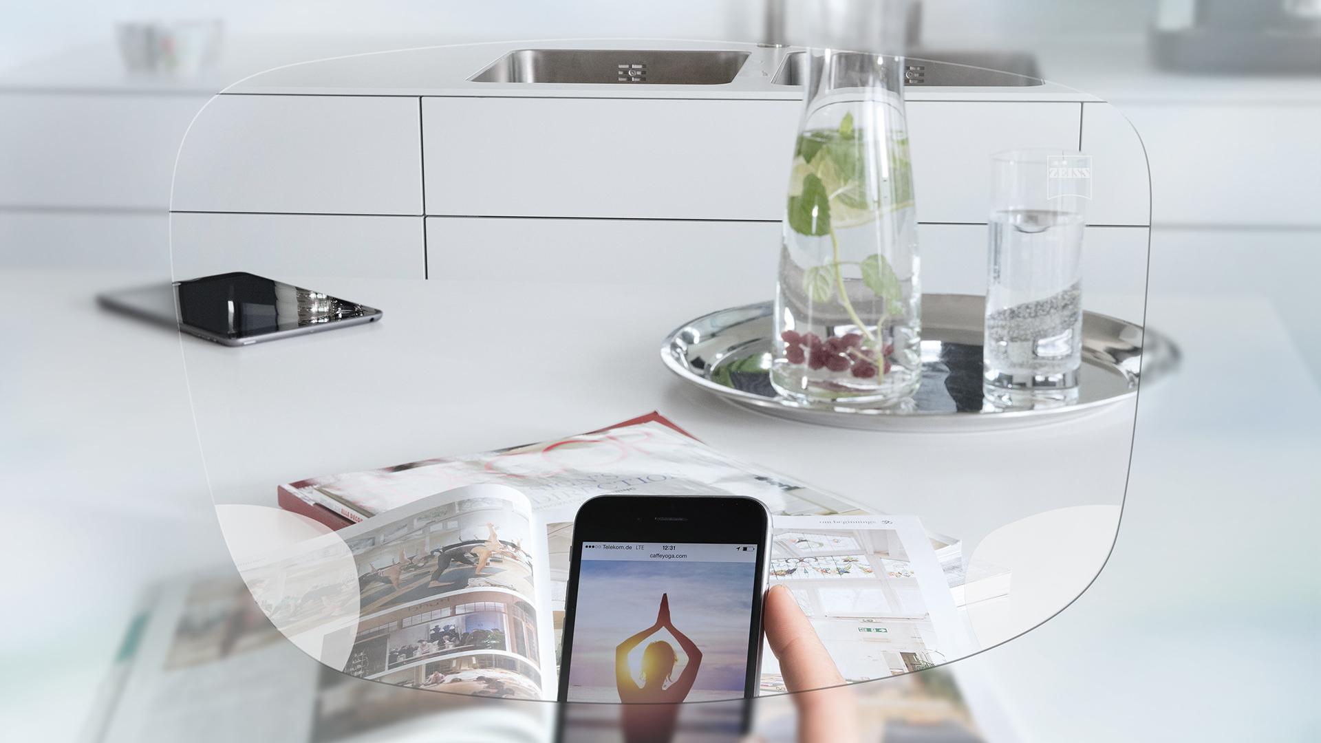 Vue de l’écran d’un smartphone et d’une table de cuisine organisée à travers les verres unifocaux ZEISS EnergizeMe. 