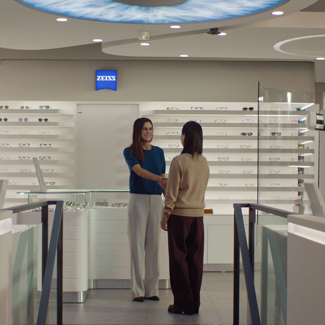 Zwei Frauen schütteln sich in einem Optikergeschäft die Hand.