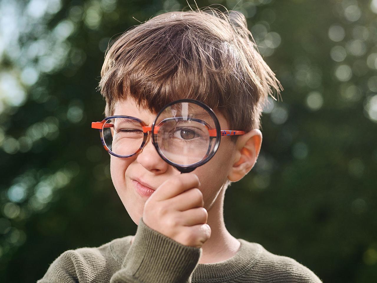 Garçon portant des lunettes utilisant une loupe 
