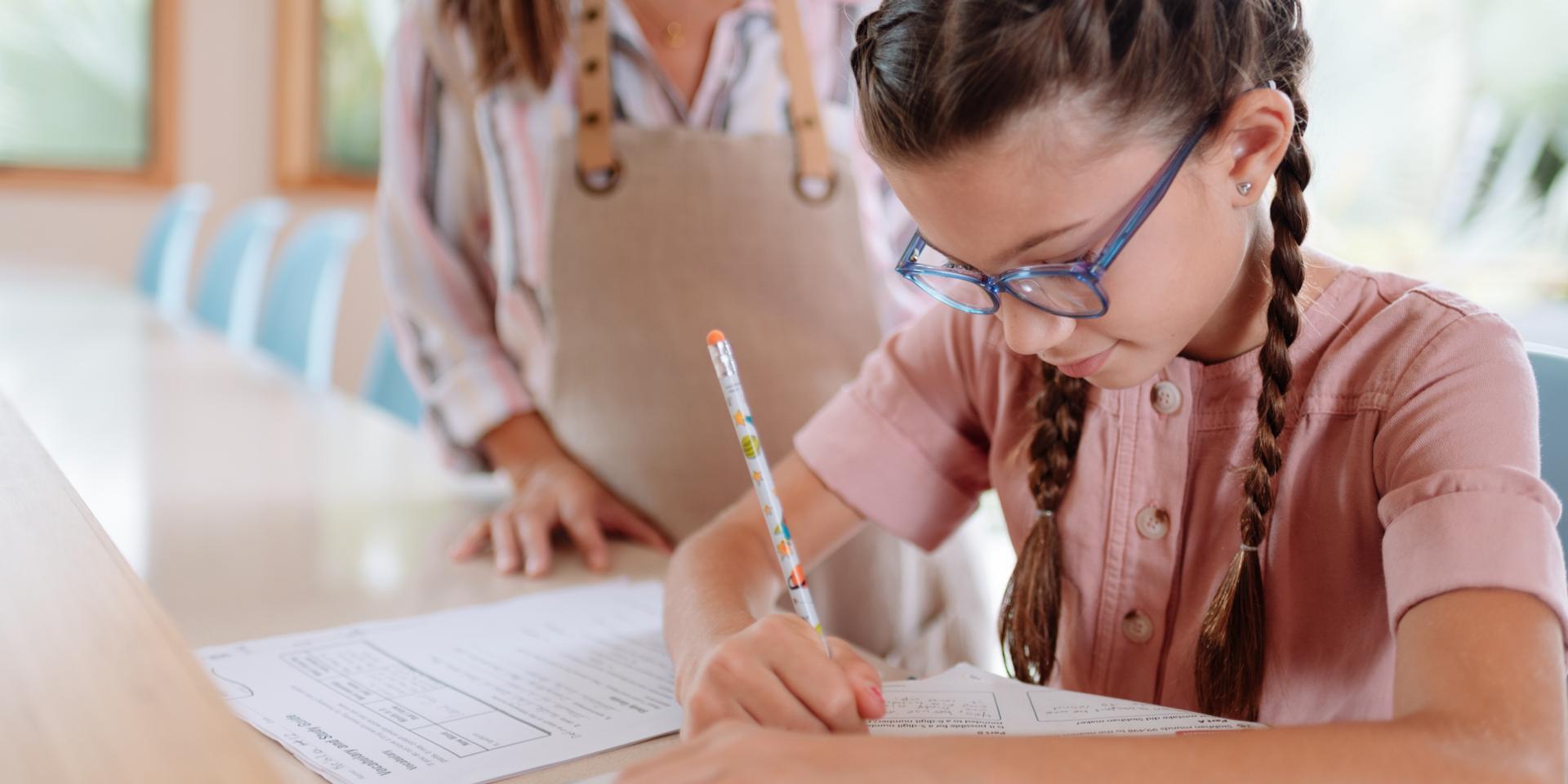 Une jeune fille portant des lunettes écrit au stylo
