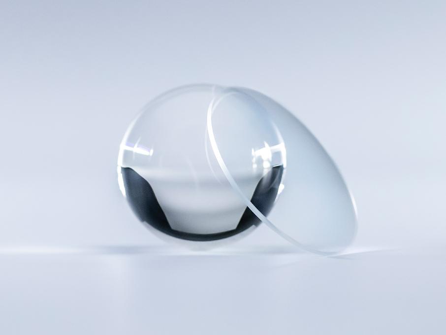 Ein Brillenglas mit ZEISS Platinum-Beschichtung ist kristallklar, ohne Reflexionen, im Gegensatz zur Glaskugel daneben.