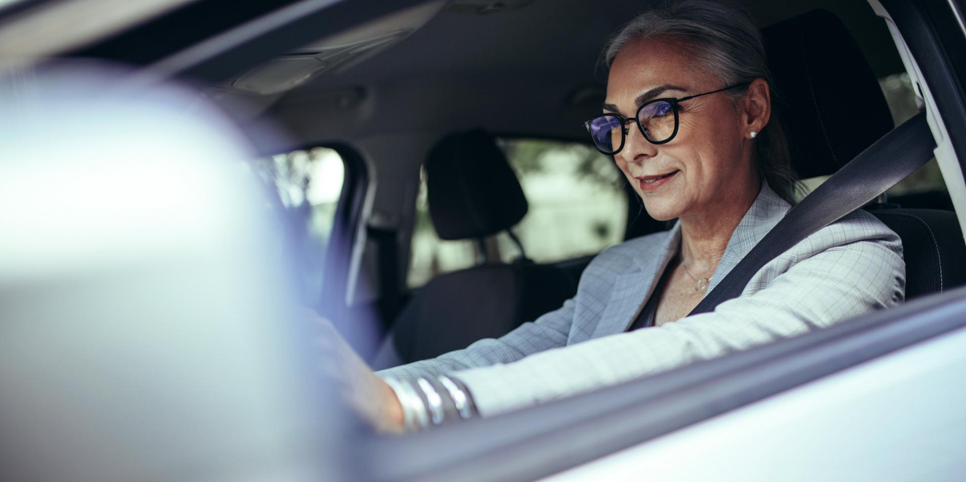 Eine Frau mittleren Alters trägt im Auto eine Brille mit ZEISS DriveSafe Brillengläsern.