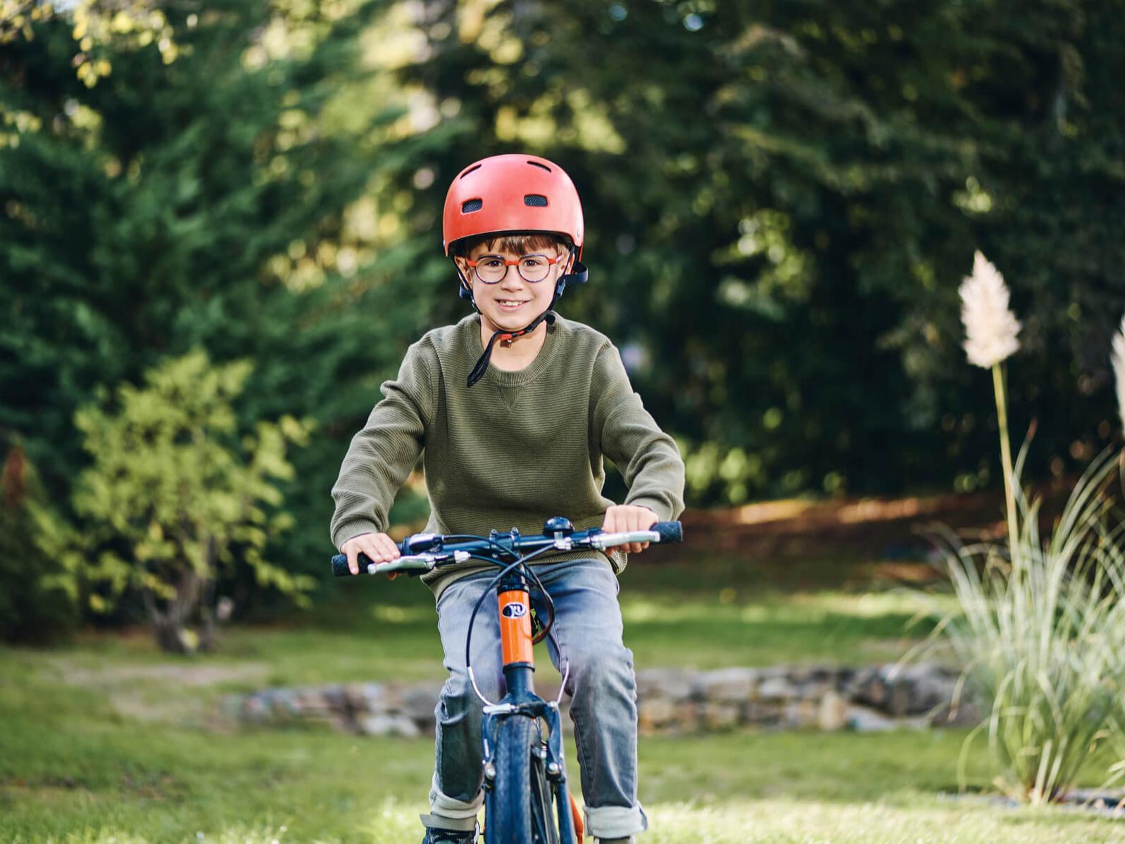 Ein kleiner Junge im Freien mit Fahrrad trägt ZEISS MyoCare Brillengläser.