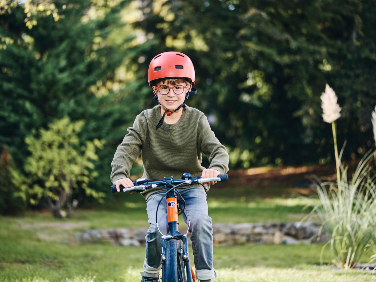 Un jeune garçon portant des verres ZEISS sur son vélo à l&apos;extérieur.