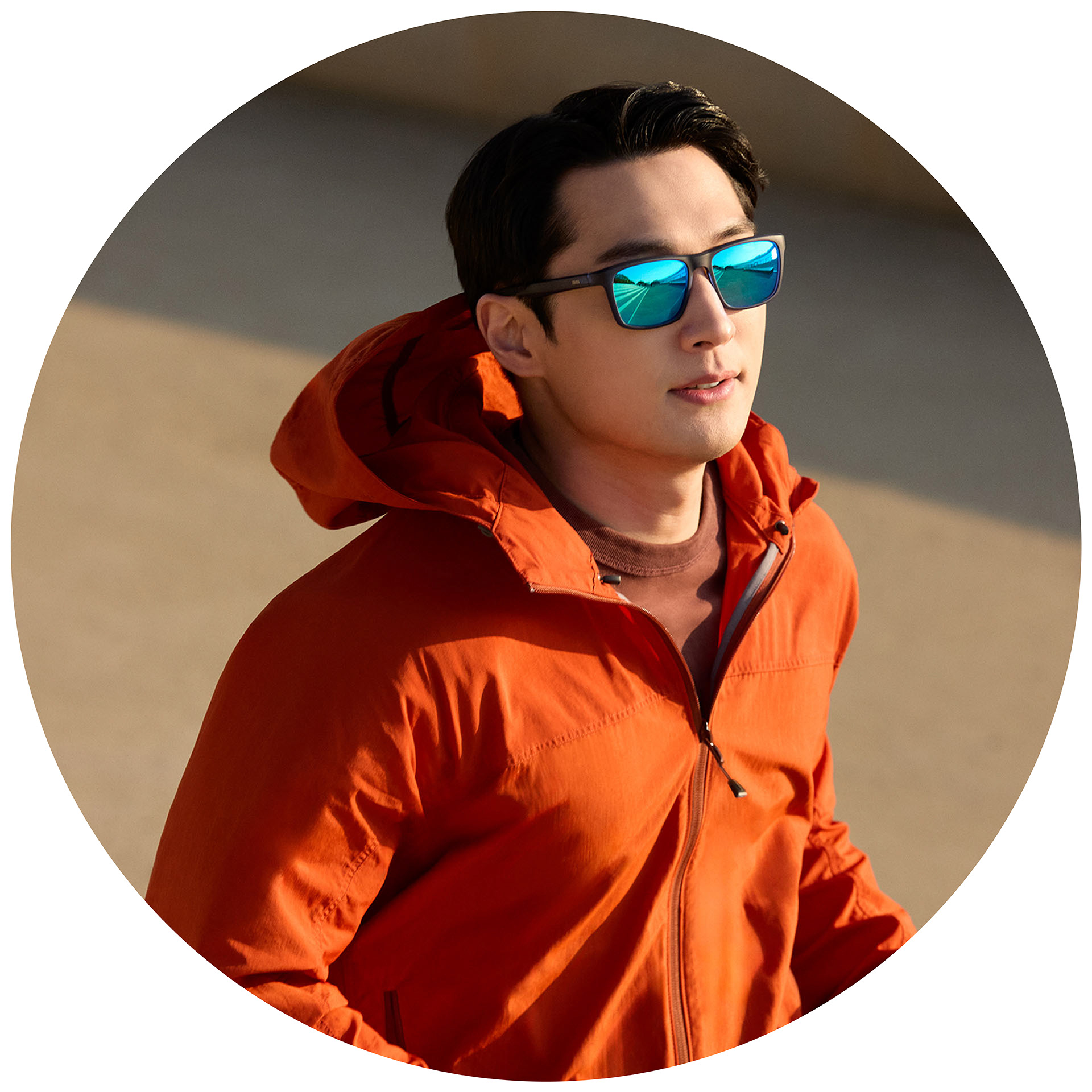 Un joggeur en veste orange porte des lunettes de soleil correctrices ZEISS avec un traitement miroir bleu.