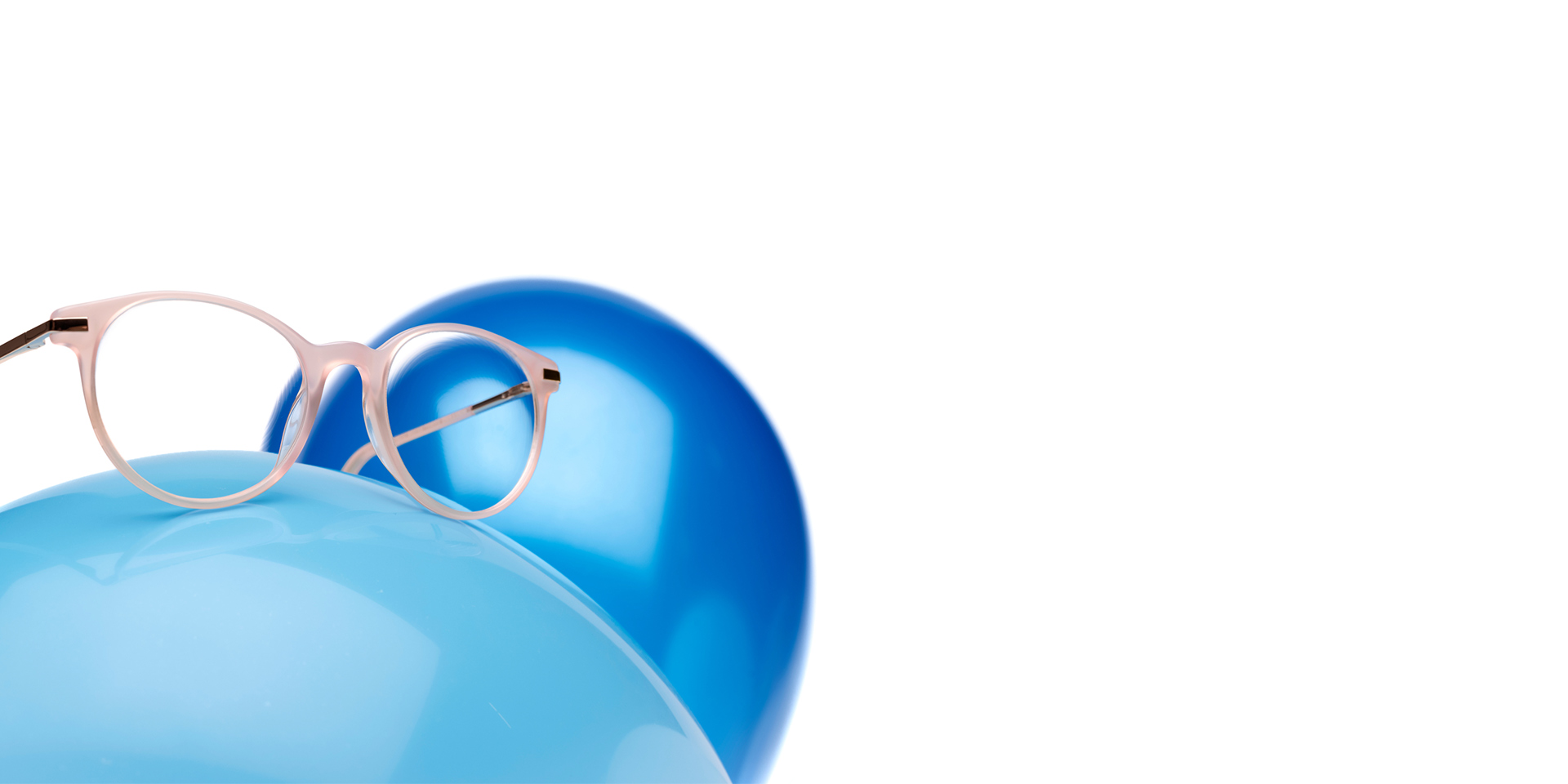 Les verres ZEISS MyoCare dans une monture beige-rosée sont présentées sur un ballon bleu clair. Un autre ballon bleu légèrement plus foncé est visible en arrière-plan.
